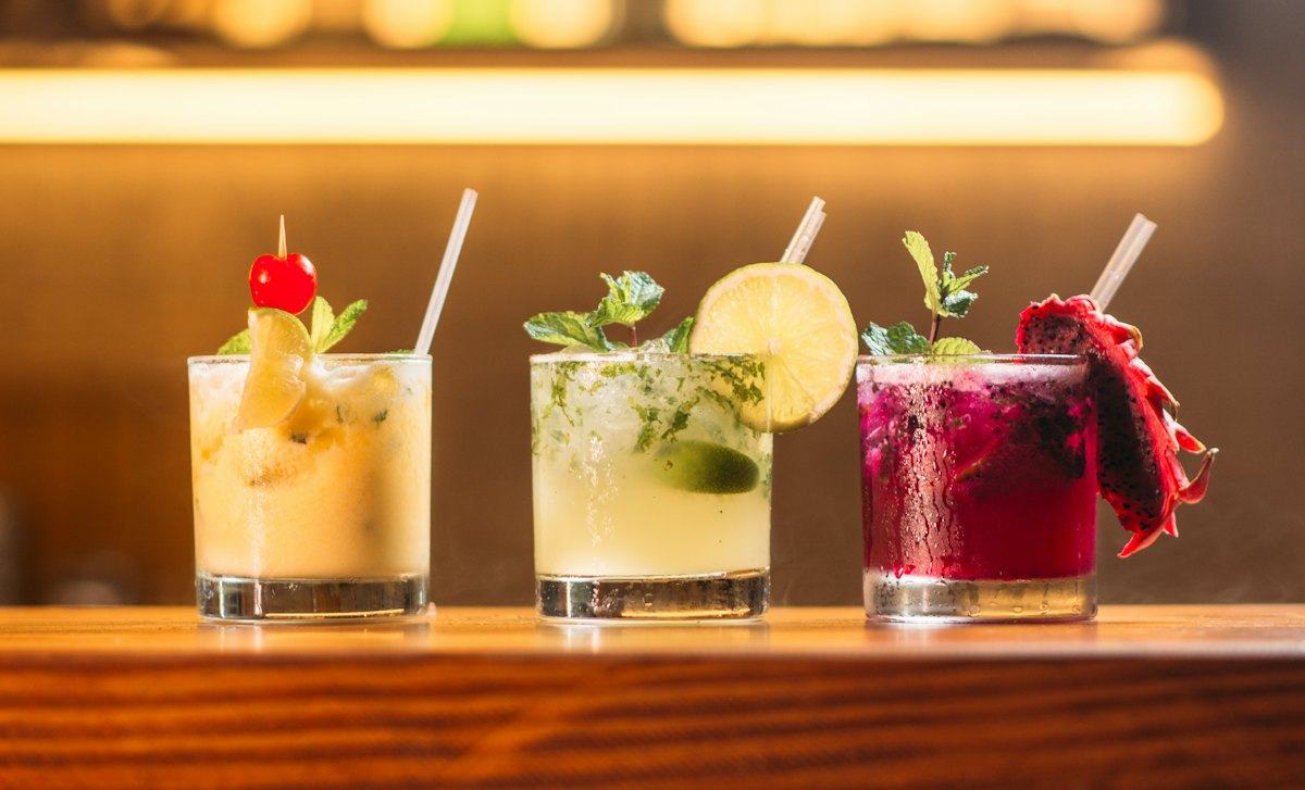 Three cocktails lined up on a bar
